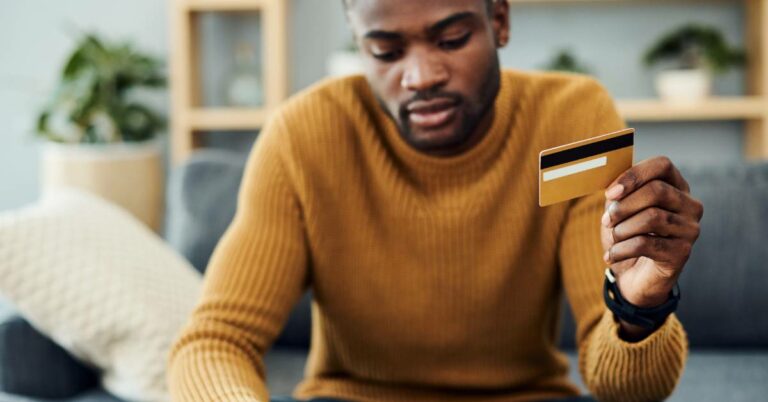 person holding a credit card in front of laptop